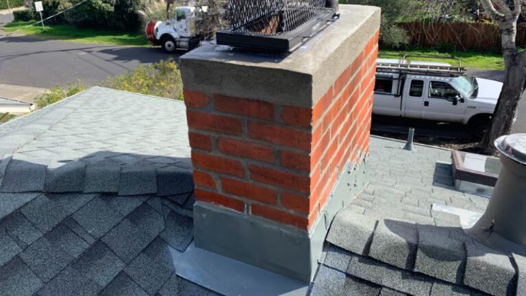 Close-up view of a brick chimney atop a gray shingled roof