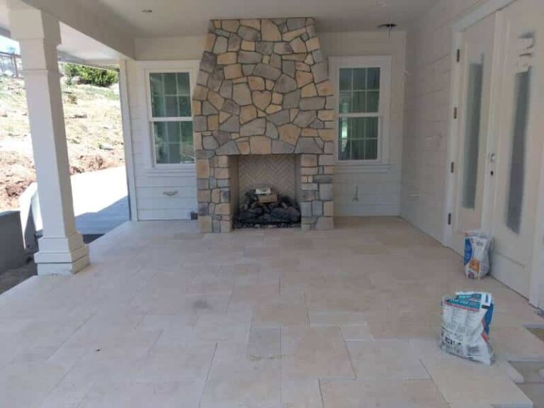 A spacious outdoor patio features a large stone fireplace as the centerpiece