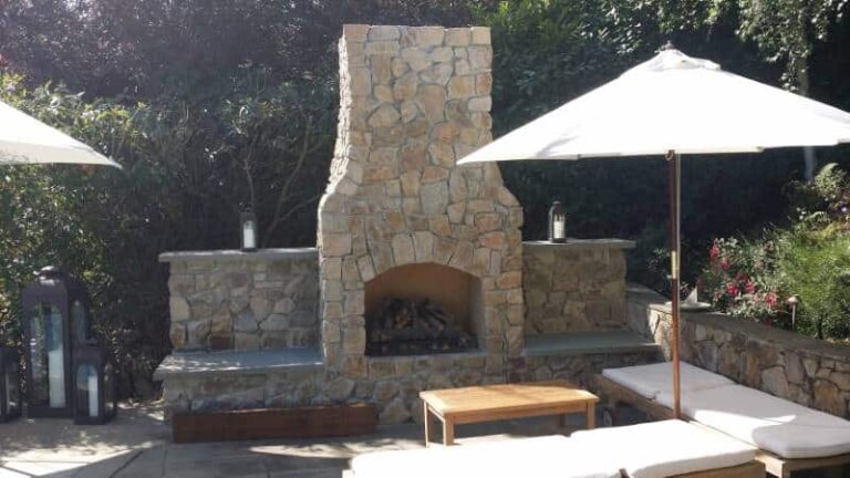 Stone outdoor fireplace with surrounding seating areas and umbrellas