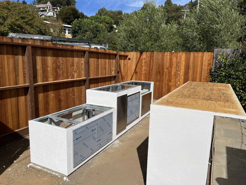 Outdoor kitchen installation in progress with built-in cabinets and countertop frame in backyard