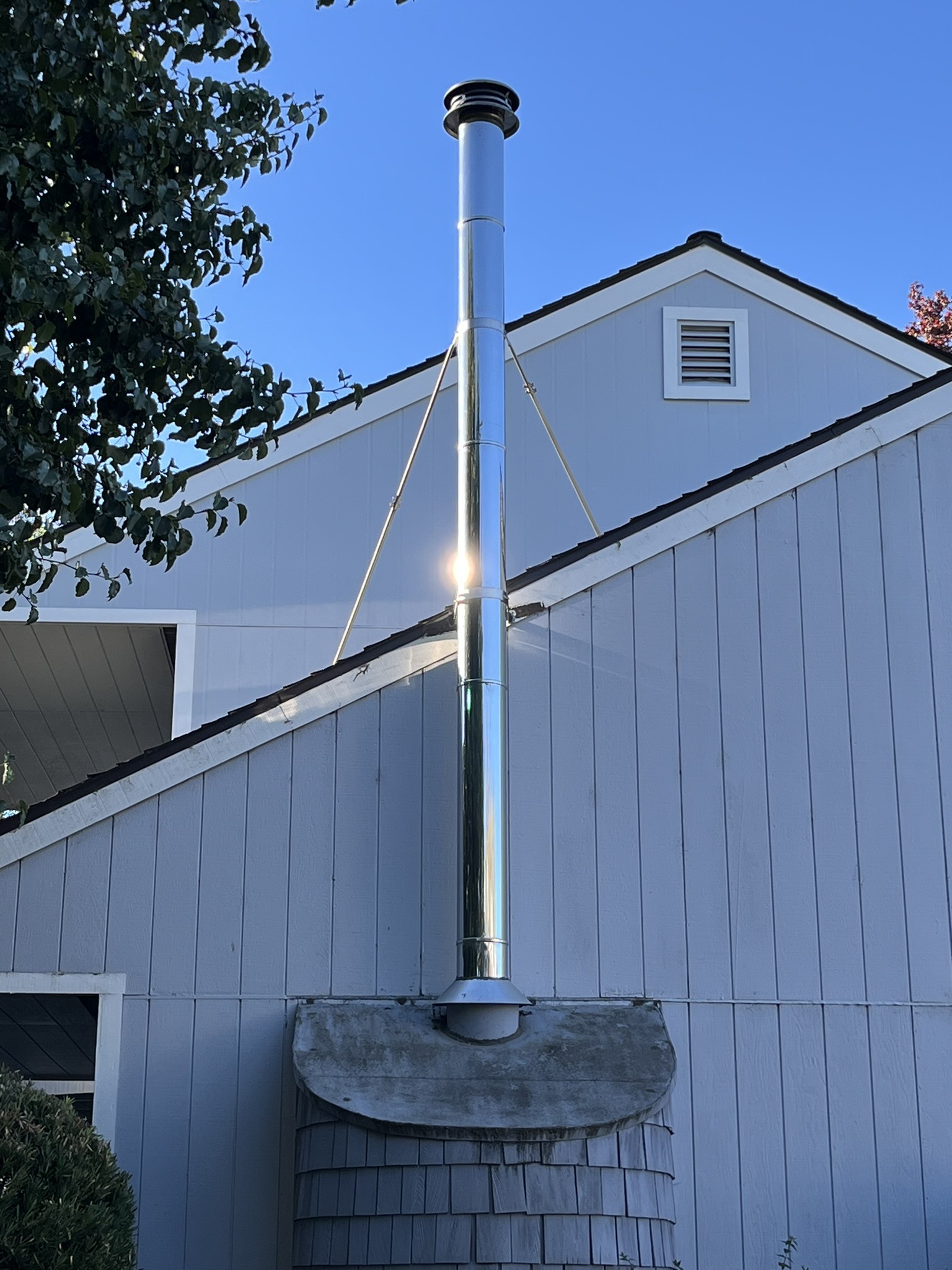 New stainless steel chimney flue rising above the roofline of a Windsor home, installed by Sierra West Co.